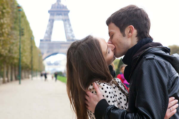 Young romantic couple kissing near the Eiffel Tower in Paris