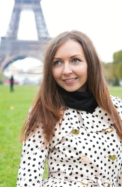 Beautiful young woman in polka dot trench near the Eiffel Tower — Zdjęcie stockowe