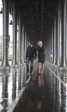 Bad weather in Paris. Couple on the bridge Bir-Hakeim at rainy w clipart