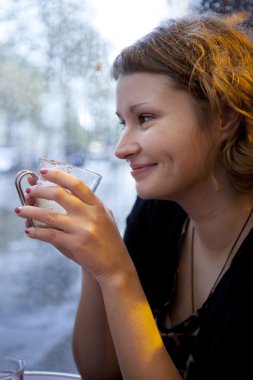 Beautiful smiling girl drinking cappuccino in a Parisian cafe at