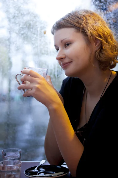 Beautiful girl drinking cappuccino in a Parisian cafe at rain — Stock Photo, Image