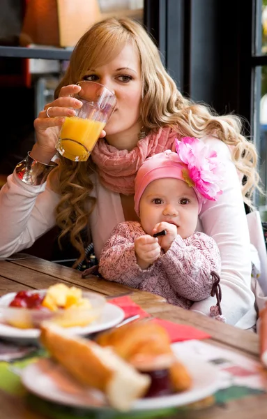Junge Mutter und kleine Tochter frühstücken zusammen in einem Pa — Stockfoto