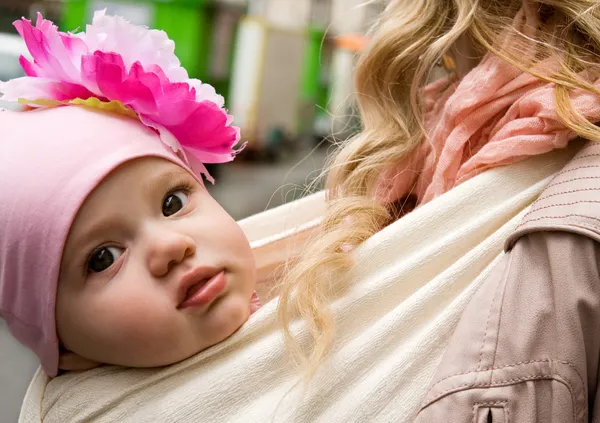 美しい女の赤ちゃんスリングで彼女の母によって運ばれる — ストック写真