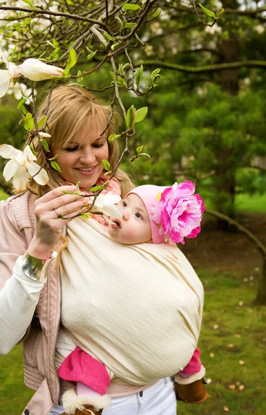 Schöne junge Mutter mit ihrer kleinen Tochter in einem Garten bei spr — Stockfoto