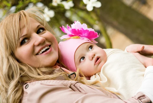 Spr で庭で彼女の赤ん坊の娘の美しい若い母親 — ストック写真