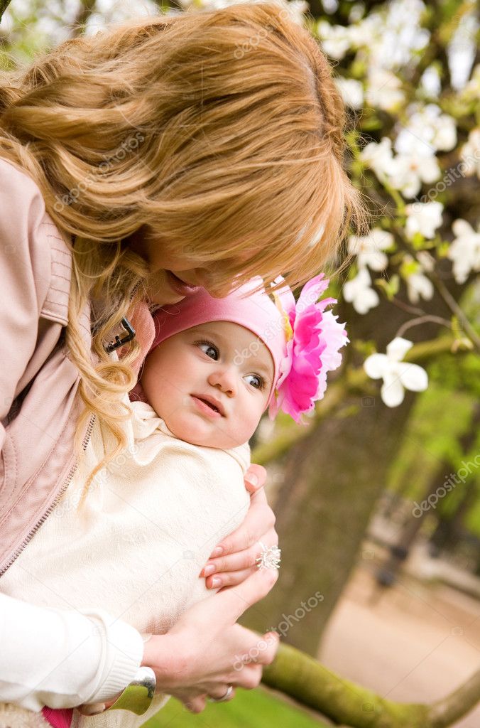 Beautiful young mother with her baby daughter outdoors at spring