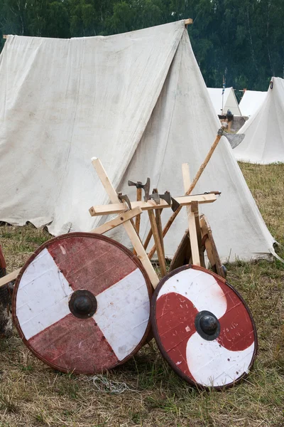 Two shield and some axes near tents Royalty Free Stock Photos