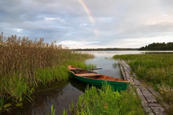 stock image Summer's lake scenery with wooden boat and rainbow