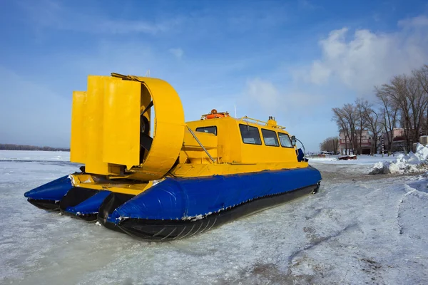 Hovercraft cruzando rio congelado contra céu azul — Fotografia de Stock
