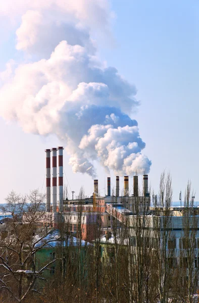 Великий завод з курильними димоходами на тлі блакитного неба — стокове фото
