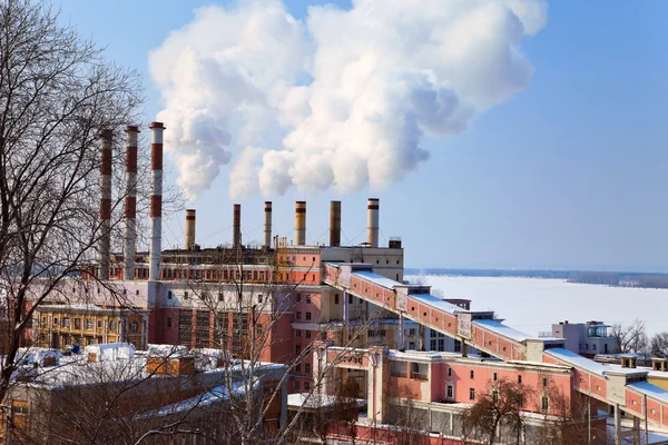 Большая фабрика с дымящимися трубами на фоне голубого неба — стоковое фото
