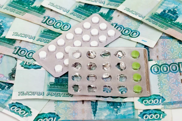 Zbliżenie tabletki na tle pieniędzy — Zdjęcie stockowe