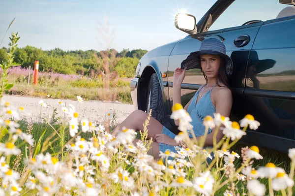 Mooie brunette vrouw zitten in de buurt van auto — Stockfoto