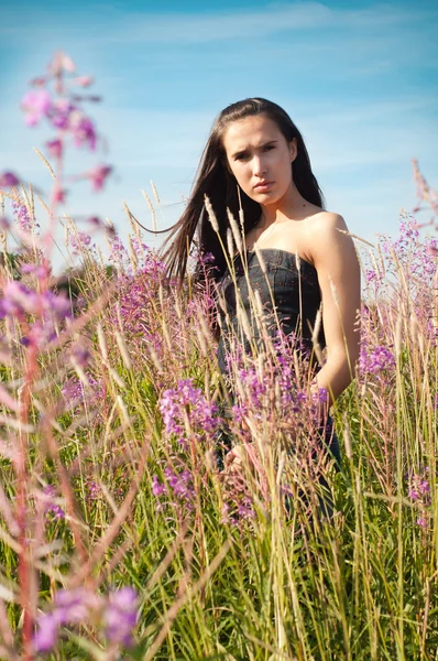 Femme debout dans l'herbe et les fleurs — Photo