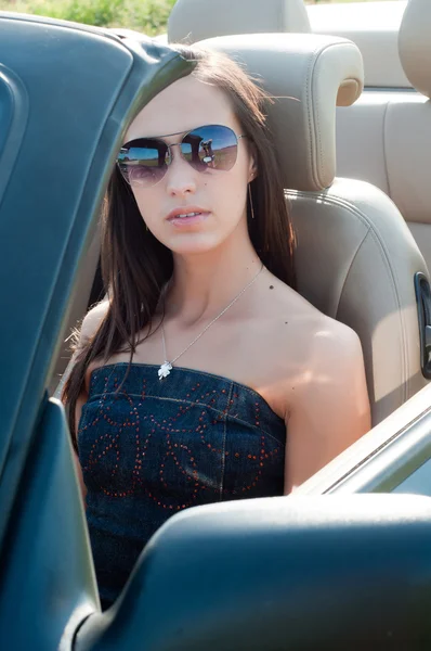 Žena v sluneční brýle sedí v cabrio — Stock fotografie