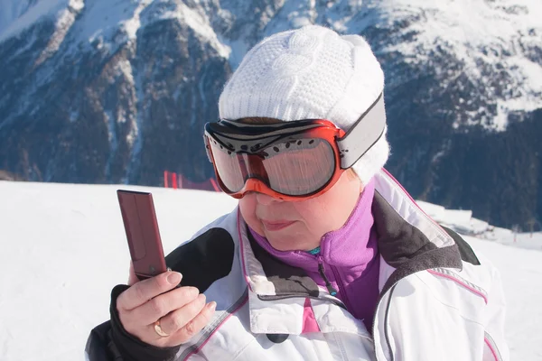 Elinde bir cep telefonu ile dağlarda kayakçı — Stok fotoğraf