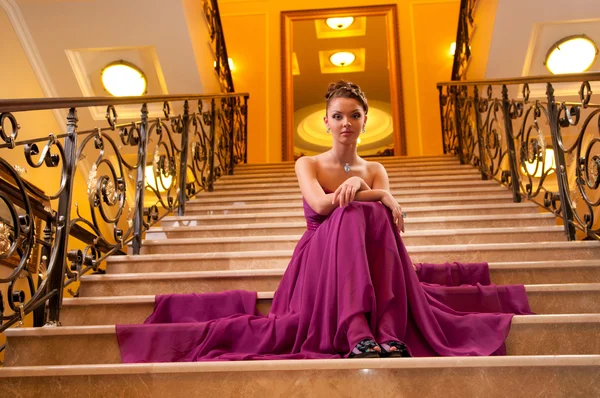 Vrouw in een lange jurk op de trap — Stockfoto