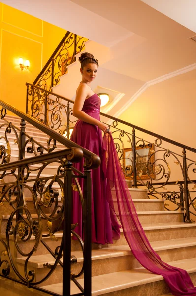 Vrouw in een sloit mooie jurk op de trap — Stockfoto
