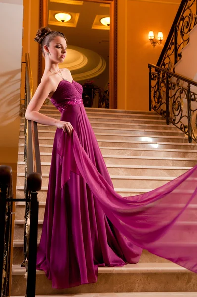 Žena v krásné šaty sloit na schodech — Stock fotografie