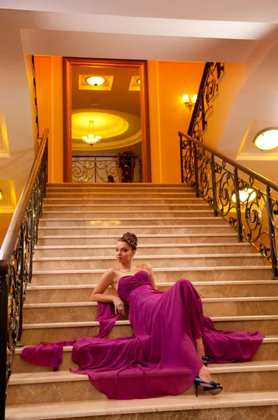 Woman in a long dress lying on the stairs — Stock Photo, Image