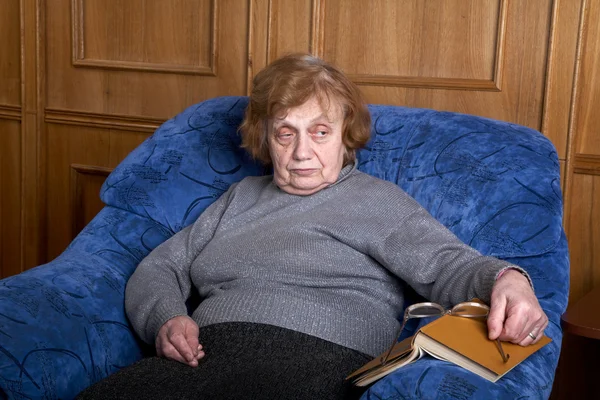 Ηλικιωμένη γυναίκα σε μια πολυθρόνα και το βιβλίο — Φωτογραφία Αρχείου