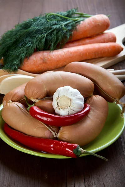 Sausages with spices and vegetables on an old table — Stock Photo, Image