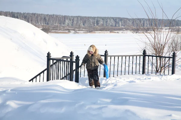 Menino com um trenó caminha lá em cima no inverno — Fotografia de Stock
