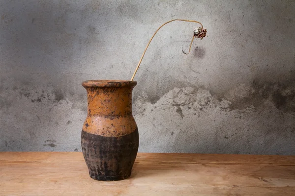 Stillleben mit einem alten Krug und trockener Pflanze auf einem Holztisch — Stockfoto