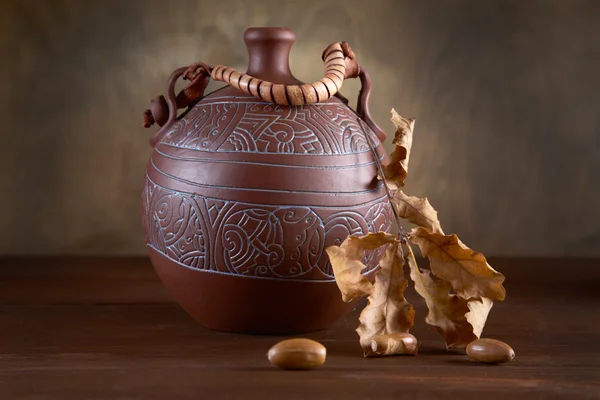 Still-life with jug and dry leaves of an oak — Stock Photo, Image