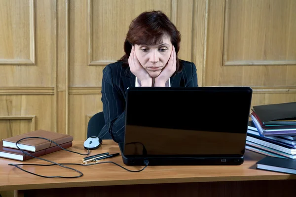 Mujer de negocios cuidadosamente mira el portátil en una oficina —  Fotos de Stock