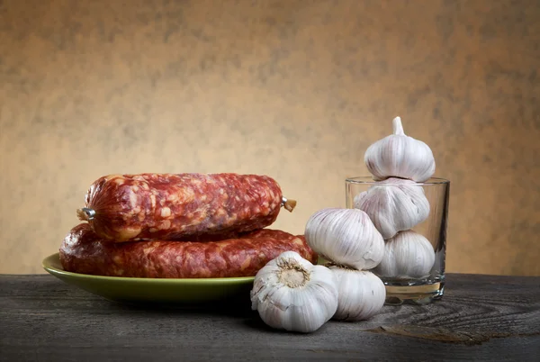 Still-life with sausage and garlic on a table — Stock Photo, Image