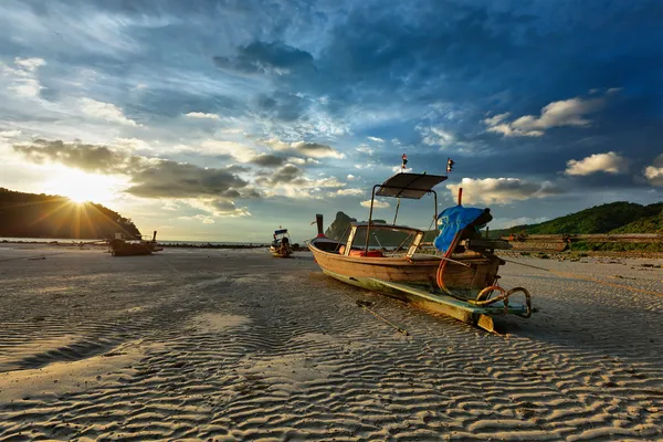 Длинная хвостовая лодка на пляже на закате — стоковое фото