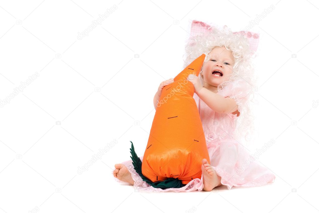 Happy baby girl plays with a carrot