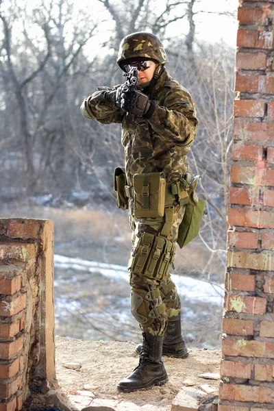 Soldat mit Waffe in Mauernähe — Stockfoto