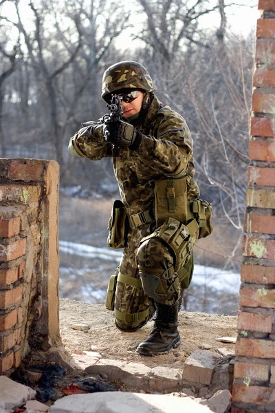 Soldat assis près du mur avec un pistolet — Photo