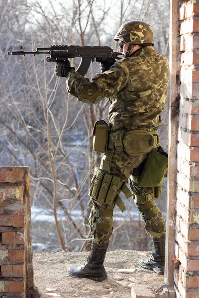 Soldado de pé perto da parede com uma arma — Fotografia de Stock