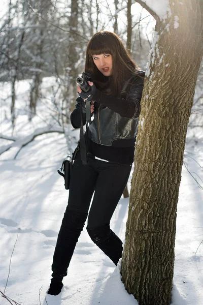 Женщина с винтовкой возле дерева — стоковое фото