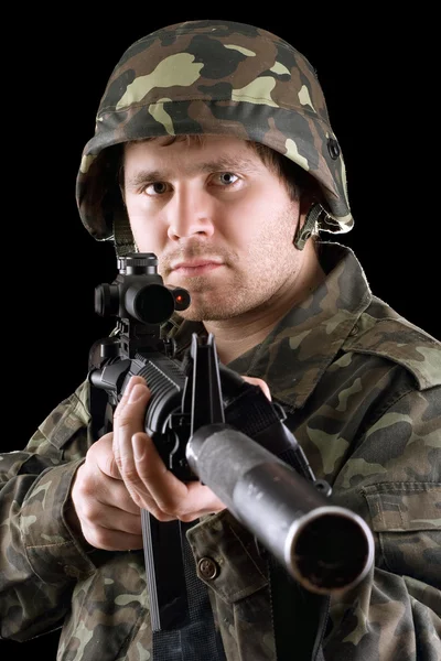 Soldier holding a gun in studio — Stock Photo, Image