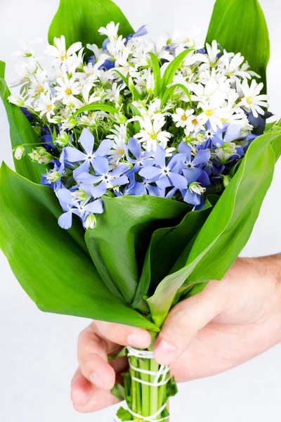 Hand of the person giving a bouquet of spring flowers — Stock Photo, Image