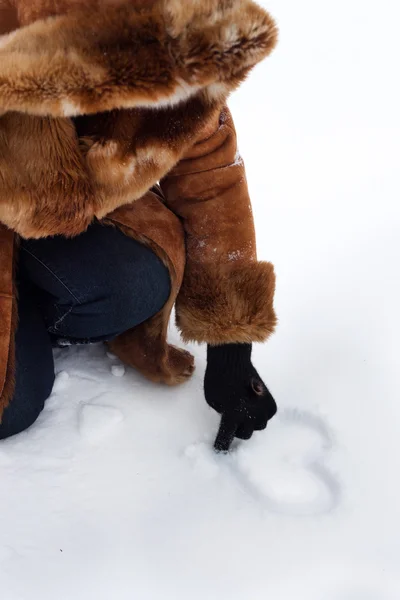 ผู้หญิงวาดหัวใจบนหิมะ — ภาพถ่ายสต็อก