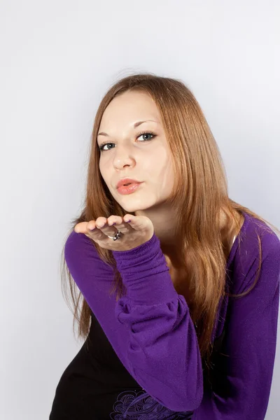 Jonge vrouw blaast op een hand (geeft een lucht-kus) — Stockfoto