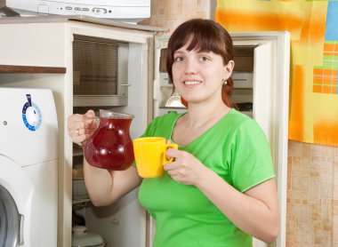 Woman pouring fruit-drink from refrigerator clipart
