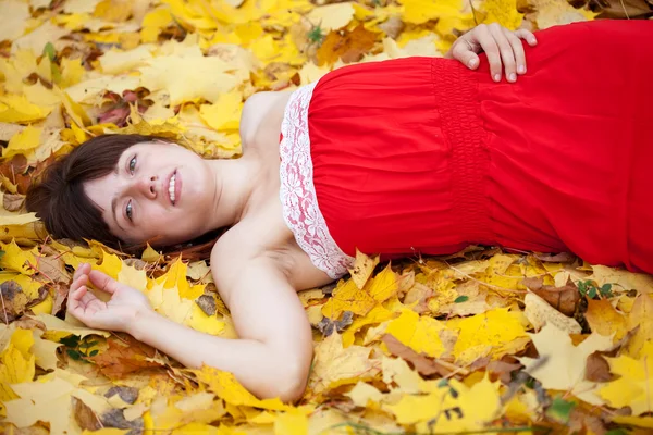Woman lies in maple leaves — Stock Photo, Image