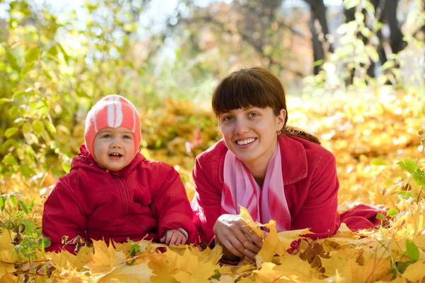 Anne ve bebek akçaağaç yaprakları üzerinde döşeme — Stok fotoğraf