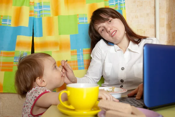 Geschäftsfrau füttert Baby und spricht per Handy — Stockfoto