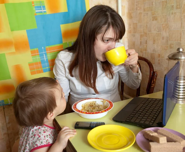 Mother feeding baby and using latop — Stock Photo, Image