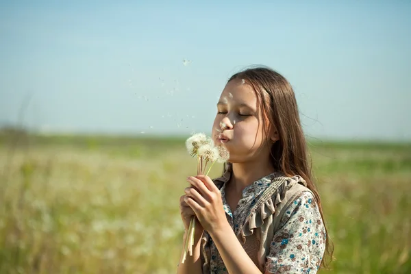 十代の女の子吹いてタンポポ — ストック写真