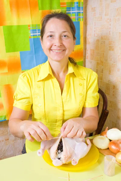 Woman sewing stuffed chicken by toothpicks — Stock Photo, Image