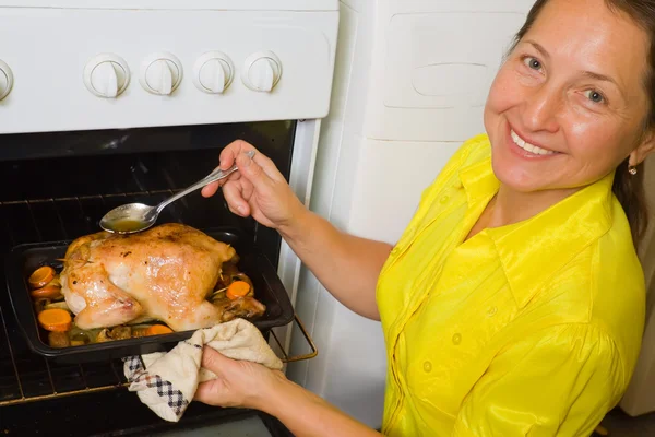 Woman cooking chicken in oven — Stock Photo, Image