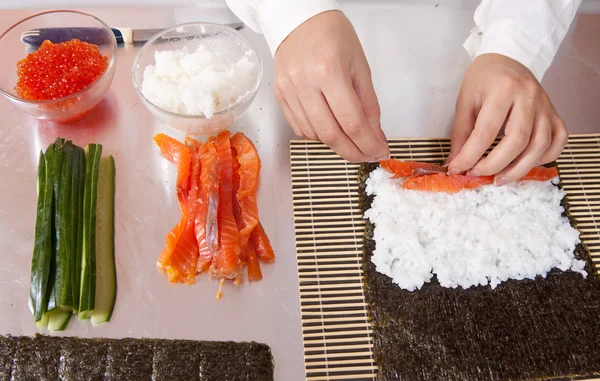 Koch macht Sushi-Brötchen mit Lachs — Stockfoto